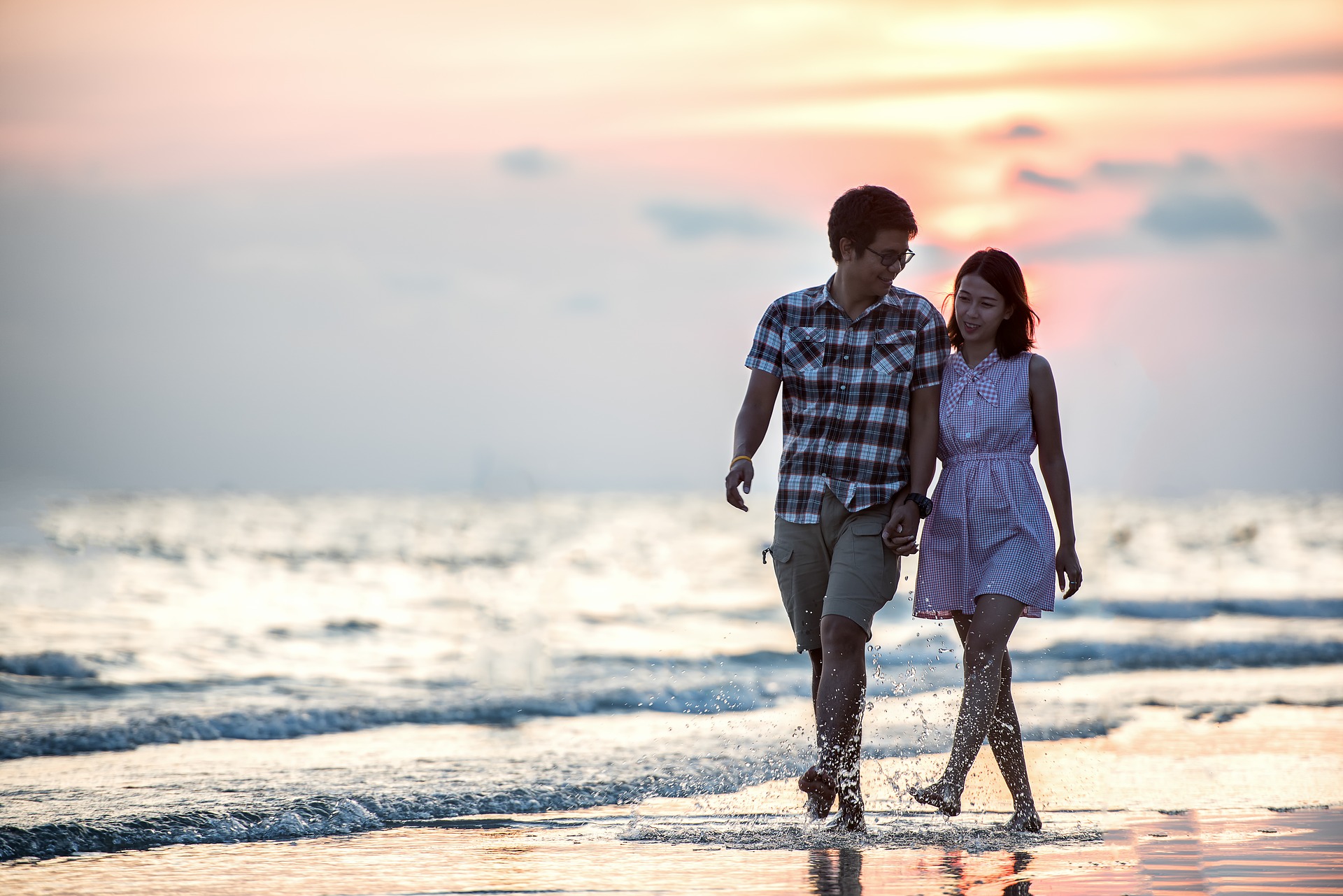 Jeune homme et femme marchant sur la plage les pieds dans l'eau